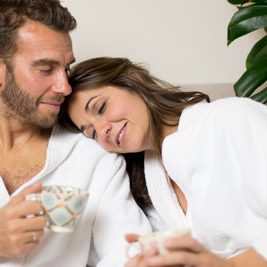 Foto a color de una pareja despues de un tratamiento en Wellness Boutique Experience Madrid. la mujer tiene la cabeza apoyada en la espalda de su marido. Están tomando una taza de té