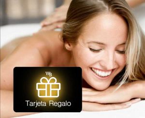 Mujer sonriente tumbada en una camilla de una lujosa cabina de masaje de Wellness Boutique Experience. en primer plano aparece una tarjeta regalo con logotipo WB en Blanco fondo negro y dorado.