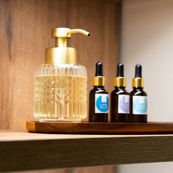 Se ve una selección de aceites esenciales de Aromatherapy associate, junto con un dispensador dorado de aceites de almendra para masaje