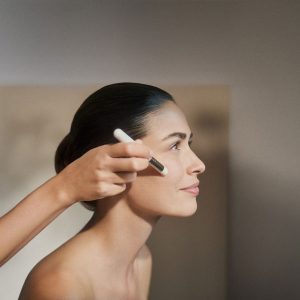 foto de una mujer joven aplicandose en el rostro un pincel durante un tratamiento facial de Natura Bissé llamado Diamond Luminous