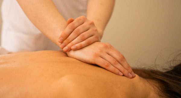 mujer recibiendo un masaje relajante de espalada en Wellness Boutique. se ve las manos de la terapeuta apoyadas en en zona de escapula